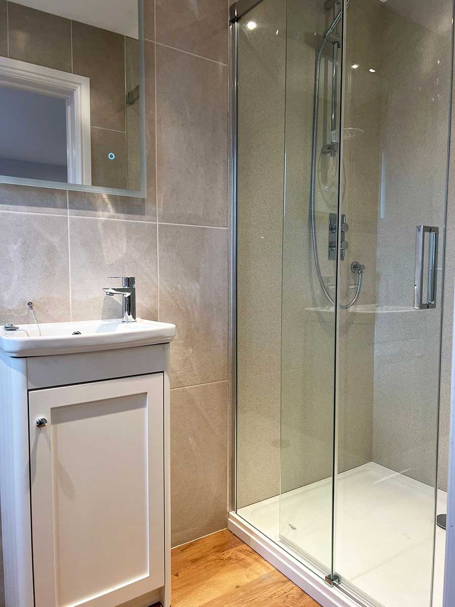 The new shower with sliding shower door and new shower wall panels installed by Room H2o