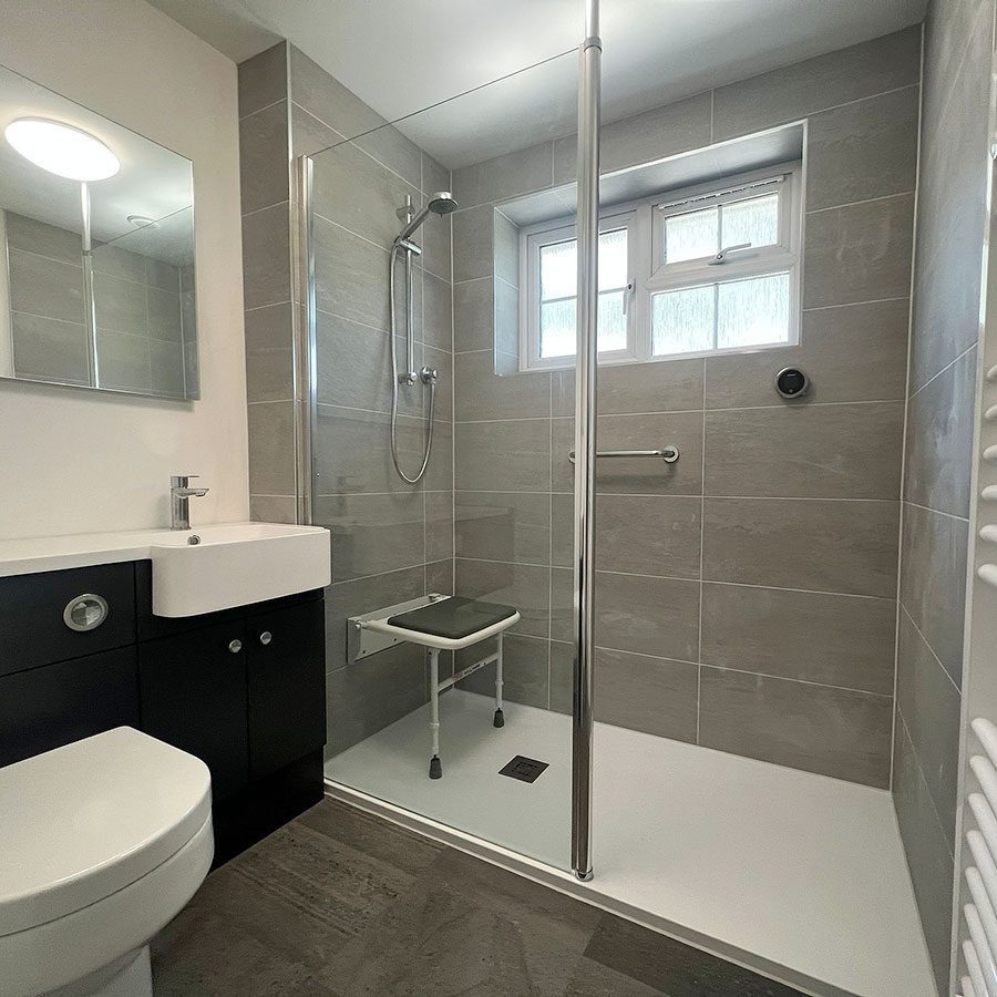 The completed disabled shower with slate effect tiles, level access shower tray, walk-in shower screen, padded shower seat and chrome grab handles